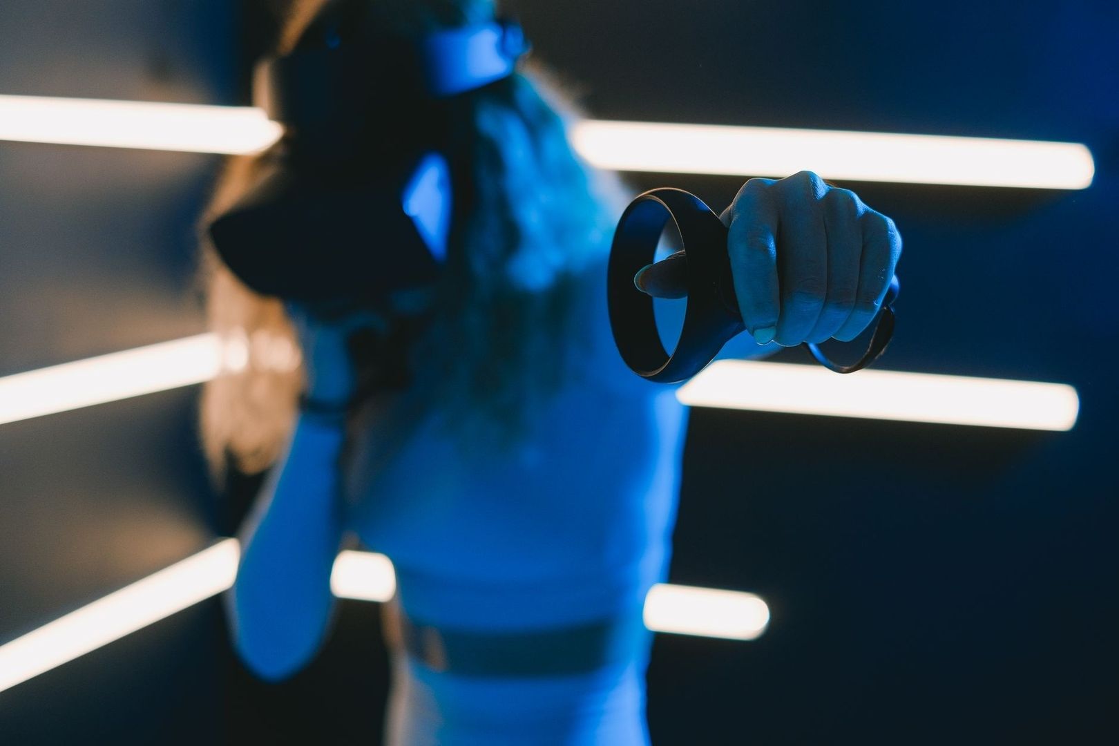 Blue-lit figure holding a virtual-reality controller in a neon grid